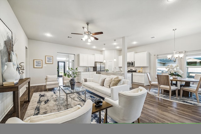 living room with ceiling fan with notable chandelier, sink, and dark hardwood / wood-style floors