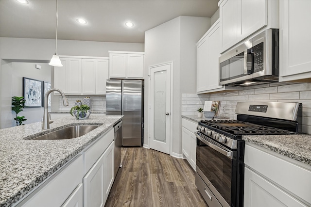 kitchen featuring white cabinetry, sink, hanging light fixtures, appliances with stainless steel finishes, and dark wood-type flooring