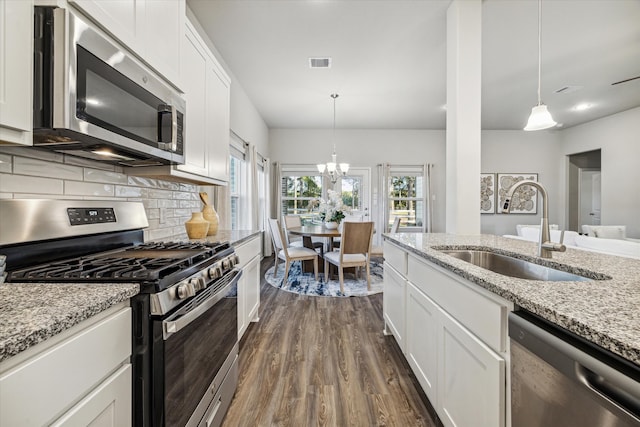 kitchen featuring sink, white cabinets, decorative light fixtures, and appliances with stainless steel finishes