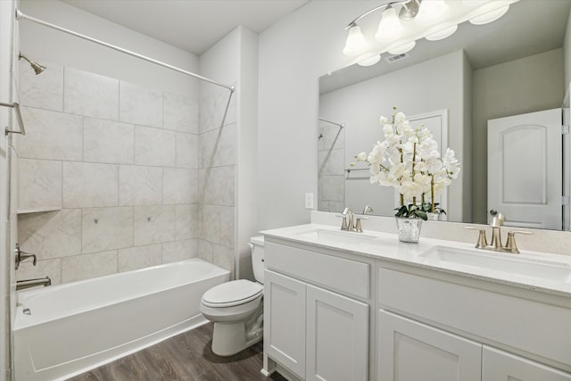 full bathroom with hardwood / wood-style floors, vanity, toilet, and tiled shower / bath