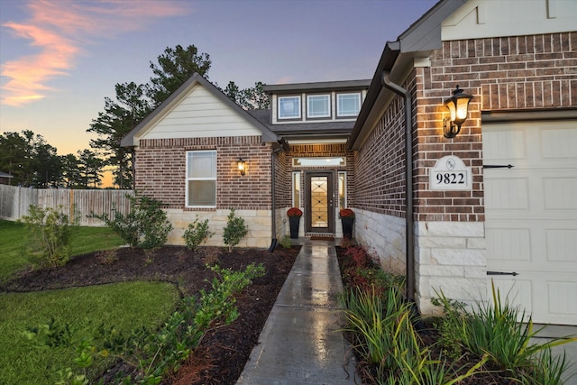 exterior entry at dusk featuring a garage