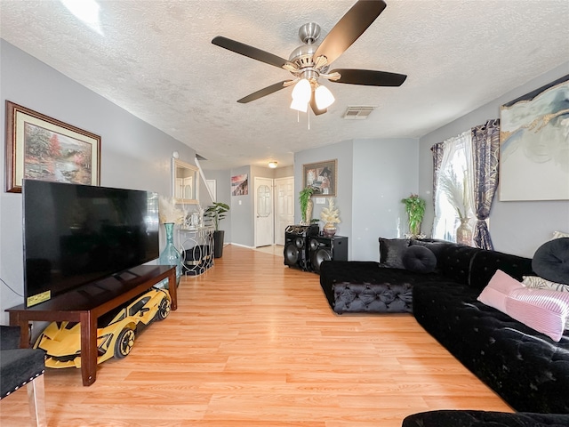 living room with ceiling fan, light hardwood / wood-style flooring, and a textured ceiling