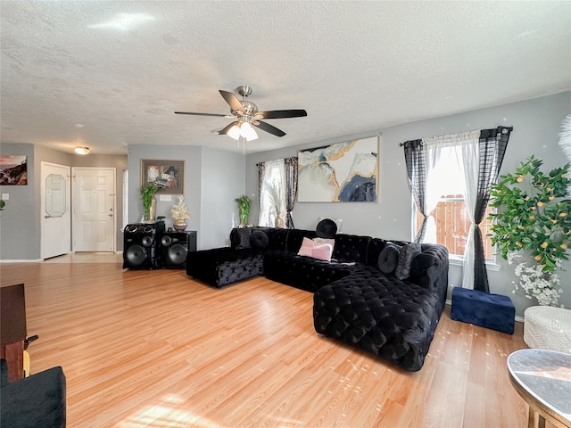 living room featuring ceiling fan, wood-type flooring, and a textured ceiling