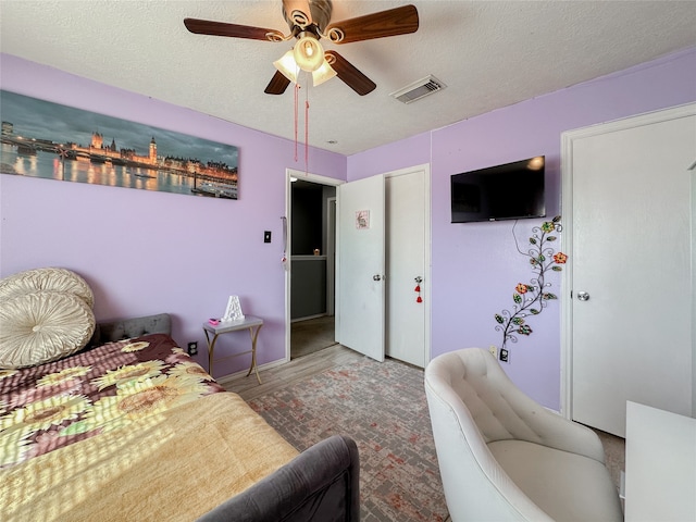 bedroom with ceiling fan, hardwood / wood-style floors, and a textured ceiling