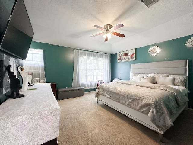 bedroom featuring carpet flooring, multiple windows, ceiling fan, and a textured ceiling