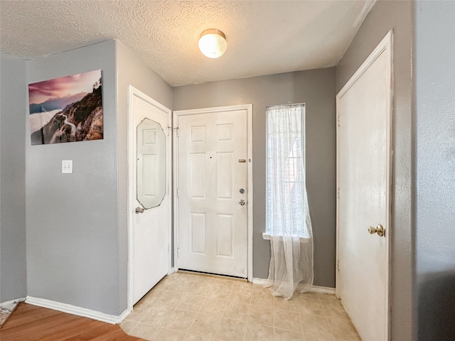 foyer entrance with a textured ceiling and light hardwood / wood-style floors