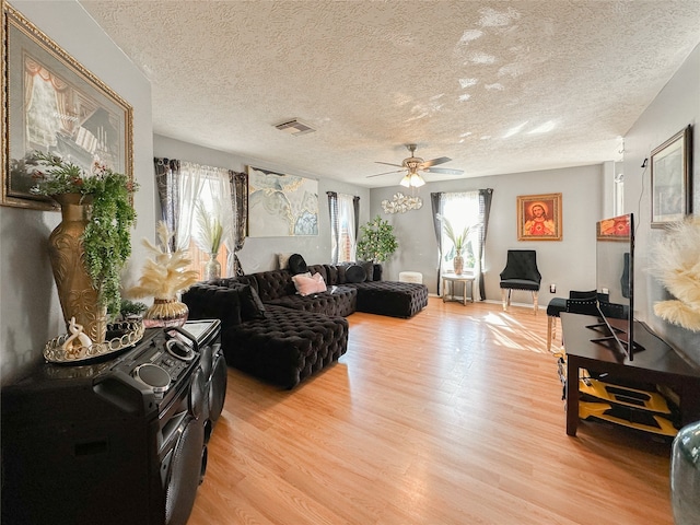 living room with a textured ceiling, light hardwood / wood-style flooring, and ceiling fan