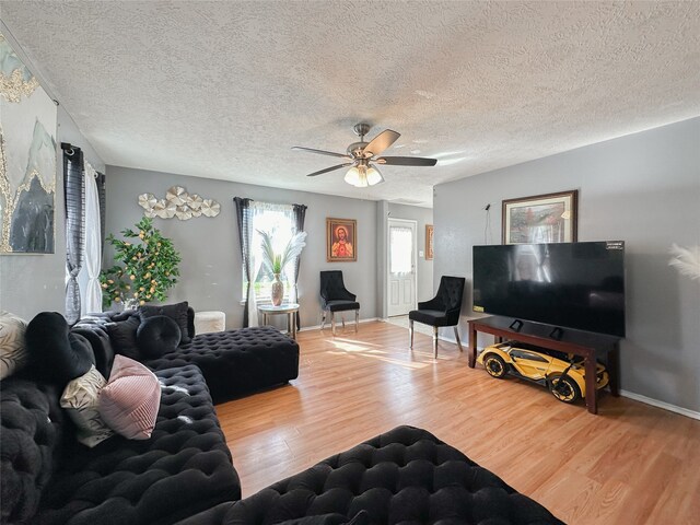 living room featuring ceiling fan, wood-type flooring, and a textured ceiling