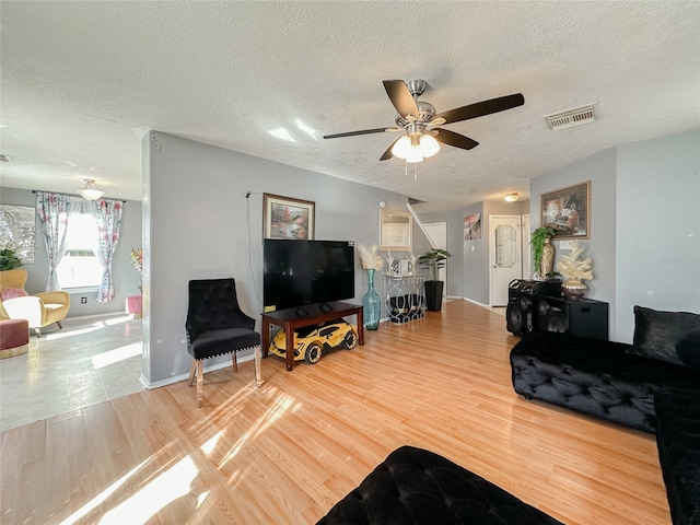 living room with ceiling fan, wood-type flooring, and a textured ceiling