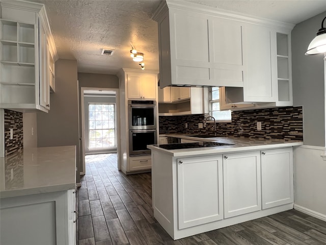 kitchen with a textured ceiling, white cabinetry, double oven, and a healthy amount of sunlight