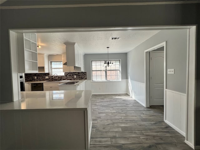 kitchen with white cabinetry, sink, backsplash, hardwood / wood-style floors, and decorative light fixtures