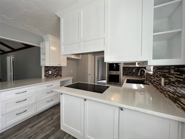 kitchen with sink, kitchen peninsula, dark hardwood / wood-style floors, decorative backsplash, and white cabinetry