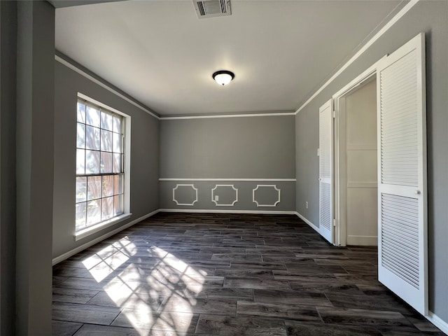 unfurnished bedroom featuring dark hardwood / wood-style floors, crown molding, and a closet