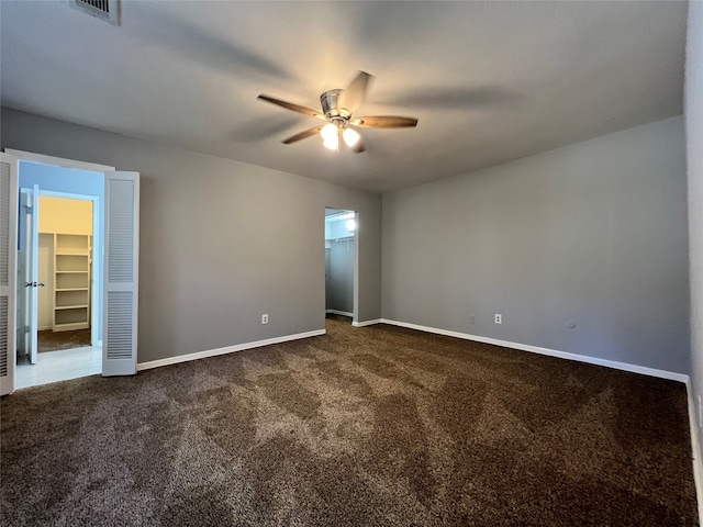 empty room with ceiling fan and dark carpet