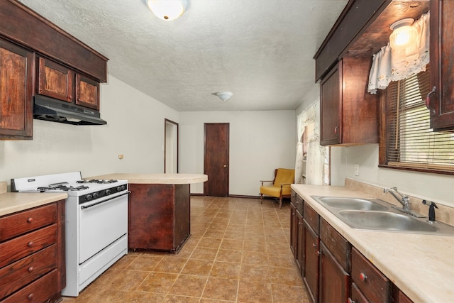 kitchen featuring kitchen peninsula, white gas range, sink, and a textured ceiling