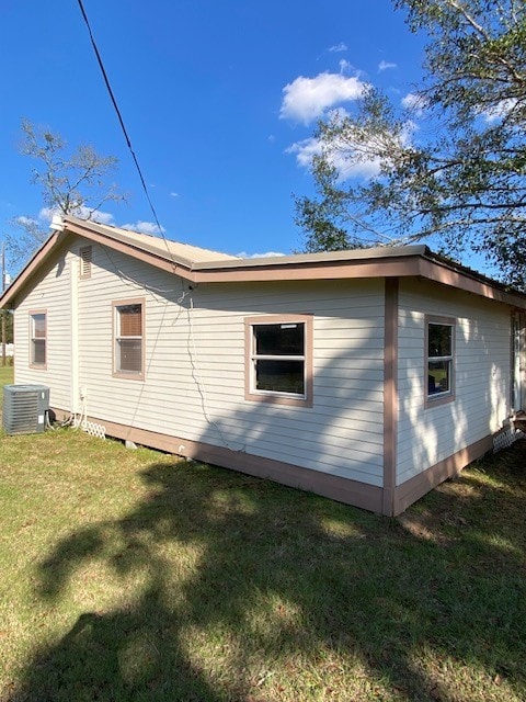 view of property exterior with central AC and a yard