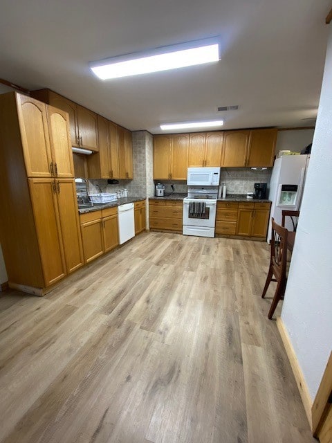 kitchen with light wood-type flooring, white appliances, and tasteful backsplash