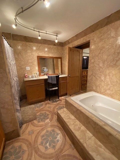 bathroom featuring vanity, rail lighting, tiled bath, and tile patterned flooring