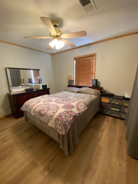 bedroom with light hardwood / wood-style flooring, ceiling fan, and crown molding