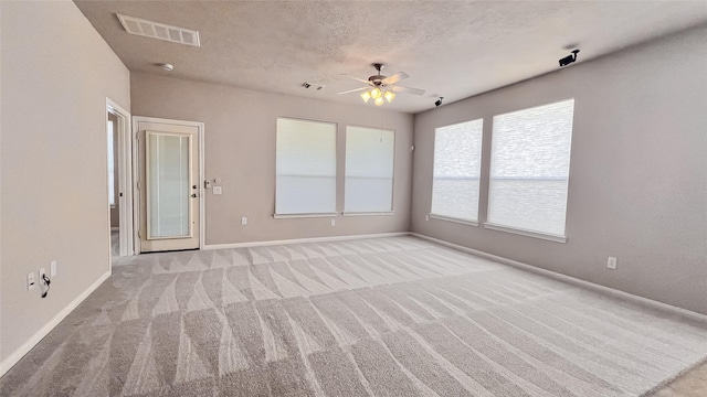 carpeted empty room featuring ceiling fan and a textured ceiling