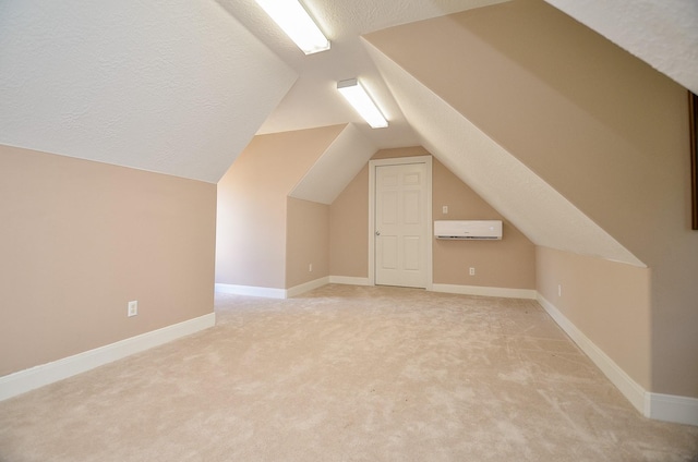 bonus room featuring lofted ceiling, a wall unit AC, light carpet, and a textured ceiling