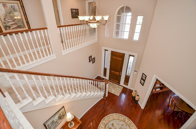 entryway with a towering ceiling, dark hardwood / wood-style floors, and a notable chandelier