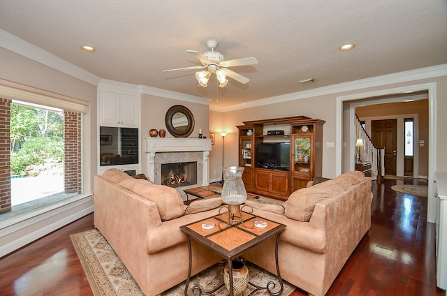 living room with dark wood-type flooring, a fireplace, crown molding, and ceiling fan