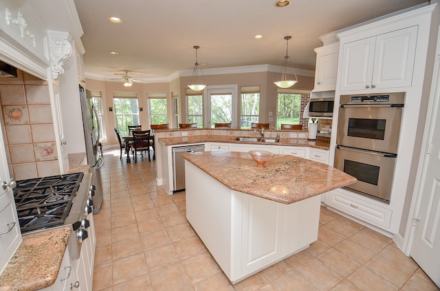 kitchen with stainless steel appliances, decorative light fixtures, kitchen peninsula, and a kitchen island