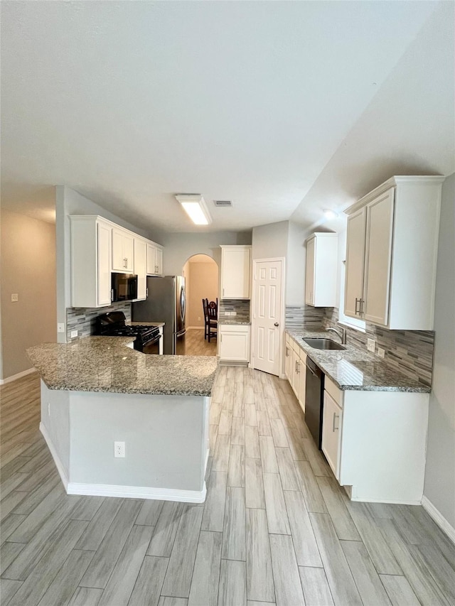 kitchen featuring white cabinetry, kitchen peninsula, light stone counters, and black appliances