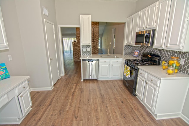 kitchen featuring light hardwood / wood-style floors, white cabinets, appliances with stainless steel finishes, and sink