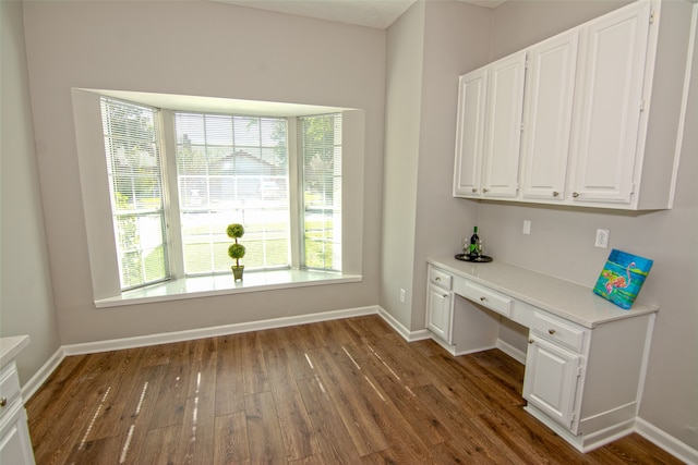 unfurnished office featuring dark wood-type flooring and built in desk