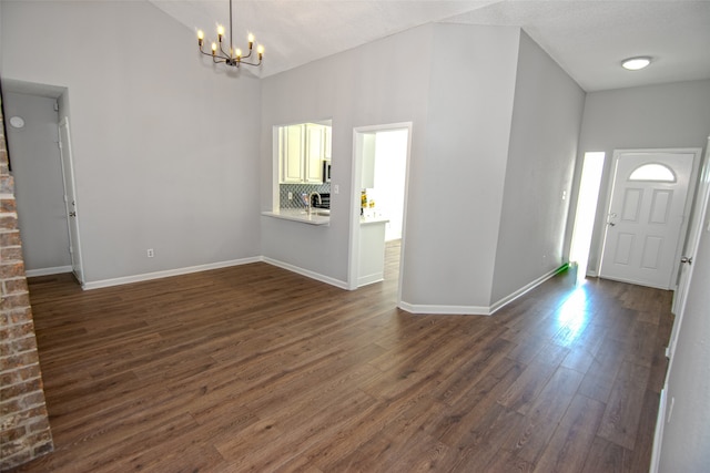 entryway featuring a textured ceiling, dark hardwood / wood-style flooring, a towering ceiling, and an inviting chandelier