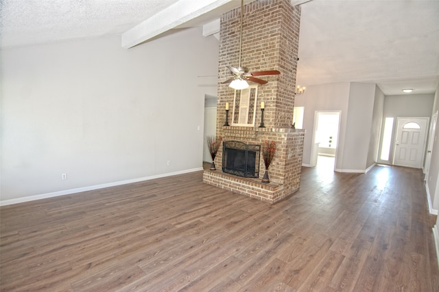 unfurnished living room featuring hardwood / wood-style flooring, ceiling fan, a fireplace, a textured ceiling, and lofted ceiling with beams