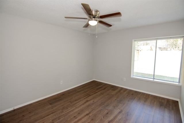 empty room with a textured ceiling, dark hardwood / wood-style floors, plenty of natural light, and ceiling fan