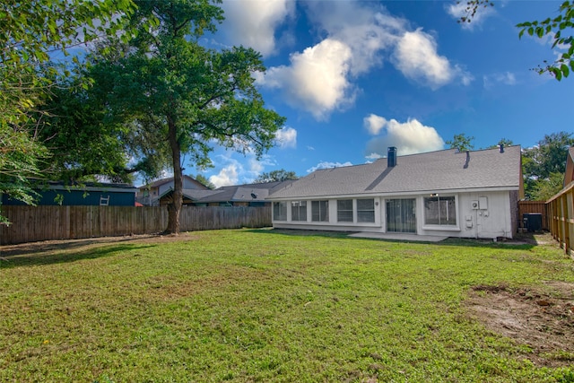 rear view of house with a lawn and central AC