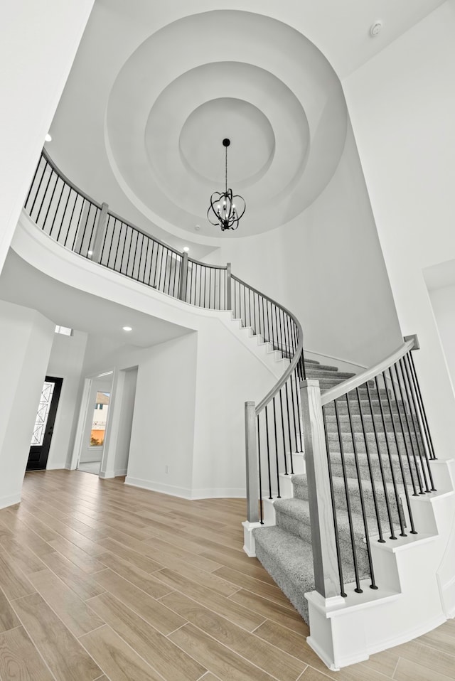 staircase with an inviting chandelier, a high ceiling, and hardwood / wood-style flooring