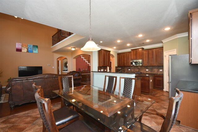 dining space with crown molding, dark tile patterned floors, and a textured ceiling