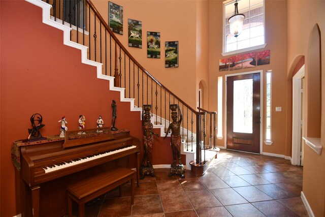 entrance foyer with a high ceiling, dark tile patterned floors, and a healthy amount of sunlight