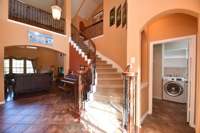 stairs with high vaulted ceiling, washer / dryer, and tile patterned floors