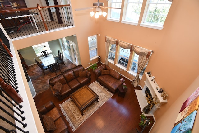 living room with a high ceiling, hardwood / wood-style flooring, and ceiling fan