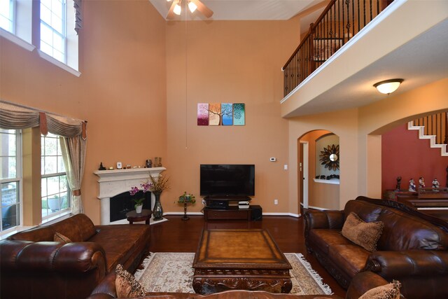 living room with a high ceiling, dark wood-type flooring, and a healthy amount of sunlight