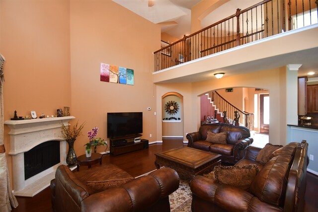 living room with a towering ceiling, dark hardwood / wood-style floors, and a healthy amount of sunlight