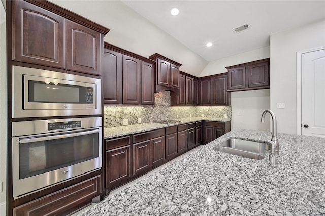 kitchen featuring light stone countertops, sink, stainless steel appliances, tasteful backsplash, and lofted ceiling