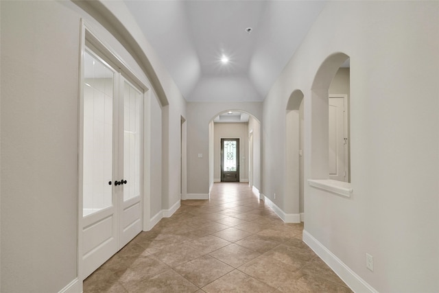 corridor with light tile patterned floors and lofted ceiling