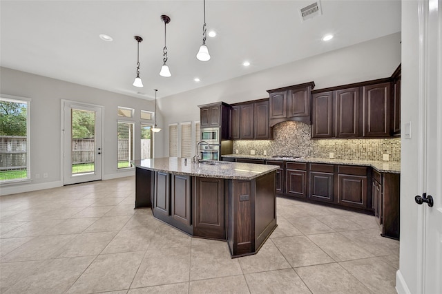 kitchen featuring appliances with stainless steel finishes, dark brown cabinets, decorative light fixtures, backsplash, and light stone countertops