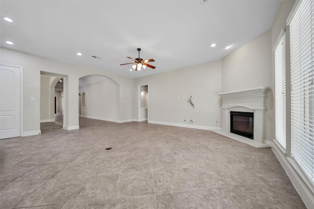 unfurnished living room with light tile patterned flooring, a wealth of natural light, and ceiling fan