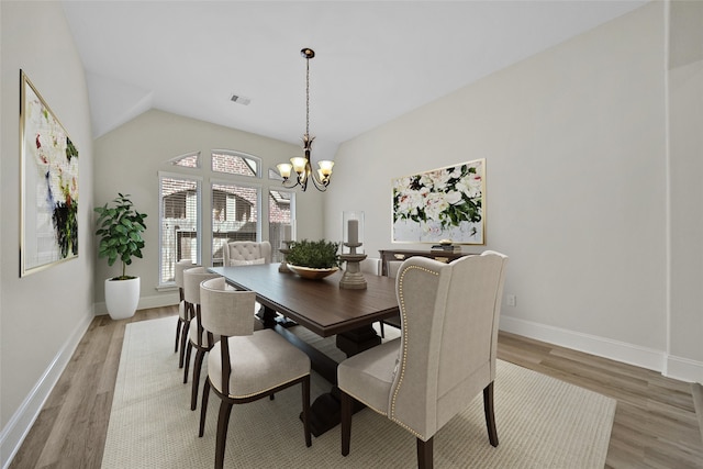 dining room featuring wood-type flooring, lofted ceiling, and a notable chandelier