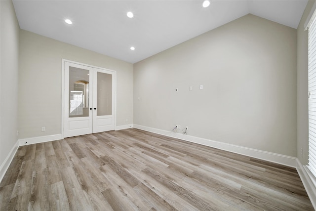 spare room featuring lofted ceiling, light hardwood / wood-style flooring, and french doors