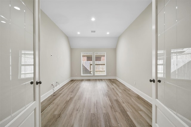 spare room featuring french doors, light hardwood / wood-style flooring, and lofted ceiling