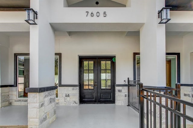 view of exterior entry featuring french doors and covered porch